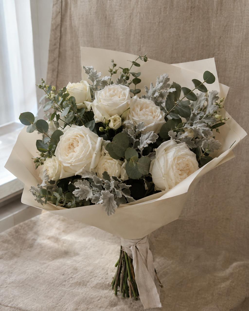 Product photograph of an author bouquet of white garden roses, eucalyptus and silver dusty miller in matte cream paper on a warm beige linen backdrop, soft window light, natural texture. Documentary photograph, real location in Russia, natural imperfect details, true-to-life colours, soft film grain, no text, no logos, no watermark, no CGI look, no glossy plastic skin, no lens flare, no neon, no holograms.
